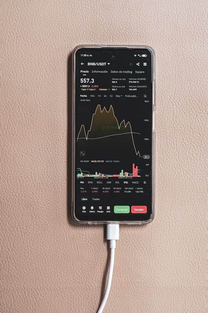 about-img Smartphone showing BNB/USDT trading chart with charging cable plugged in.