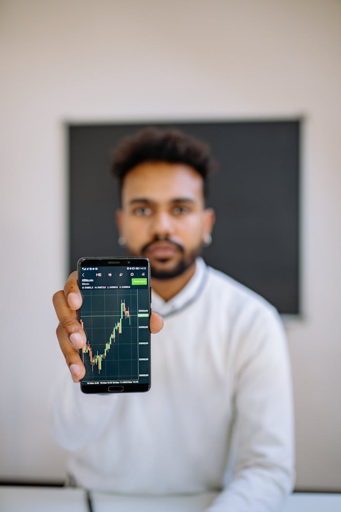 our-experience Man holding smartphone with stock market chart, focusing on financial growth.